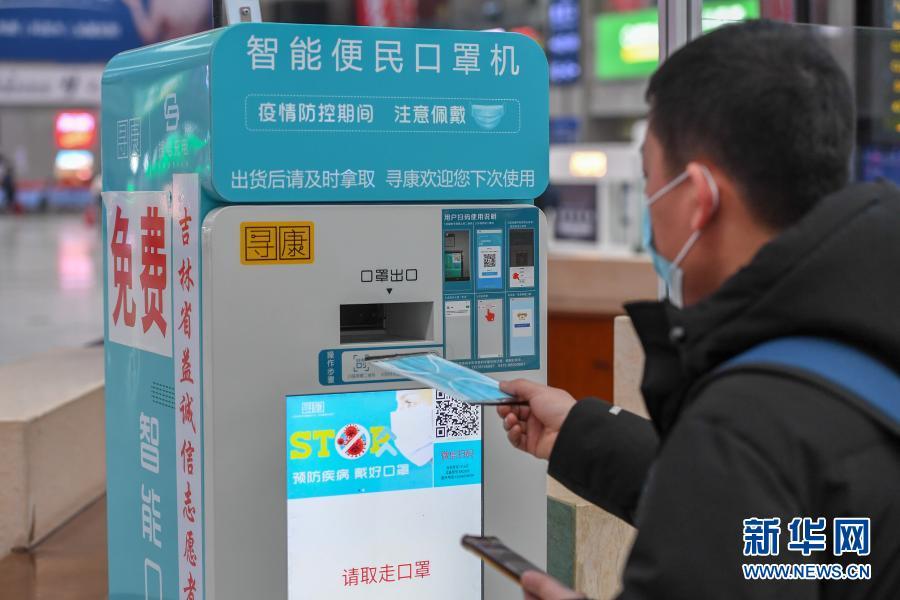 1月28日，在长春站候车大厅，一位旅客使用便民口罩机领取免费口罩。新华社记者 张楠 摄
